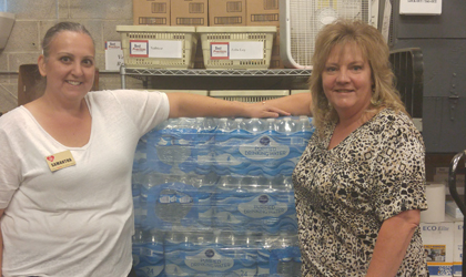 An EUCCU employee standing next to a pallet of waters to be donated for relief from the Texan hurricane.